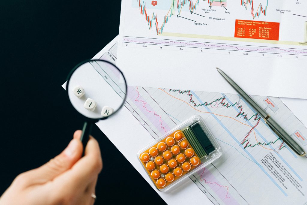 Magnifying glass highlighting the word 'WIN' over financial charts. Enhance your business analysis vision.